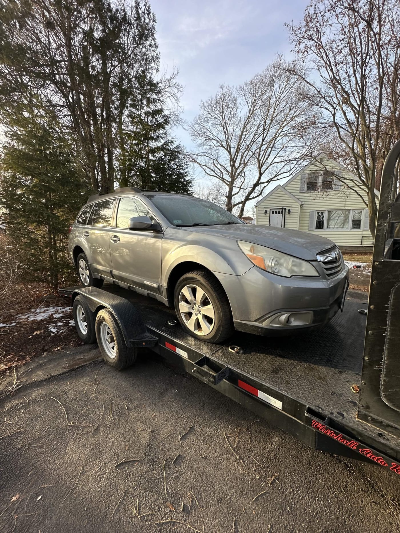 A Subaru loaded on our trailer for free pickup in a snowy New England driveway